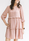 Model wearing a blush above the knee lined dress with 3/4 bubble sleeves and tiers with ruffles. 