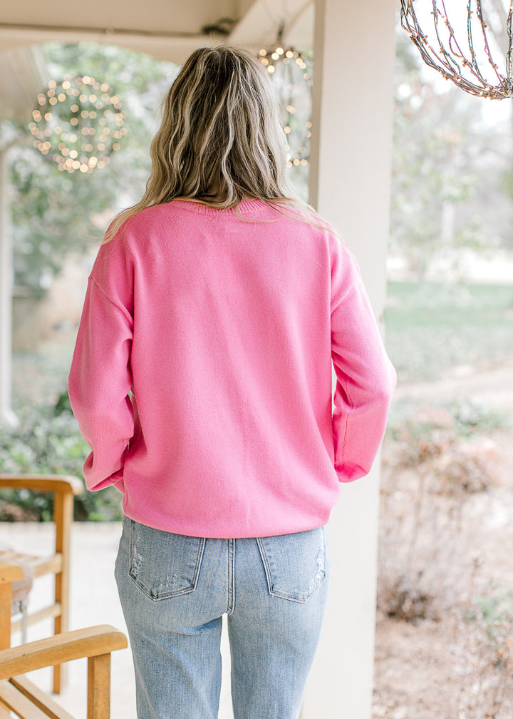 Back view of Model wearing a hot pink sweater with a cream heart design along the front.