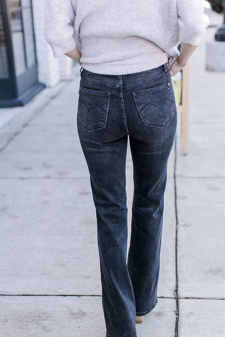 Back view of Model wearing black jeans with tummy control, high waist and bootcut fit.