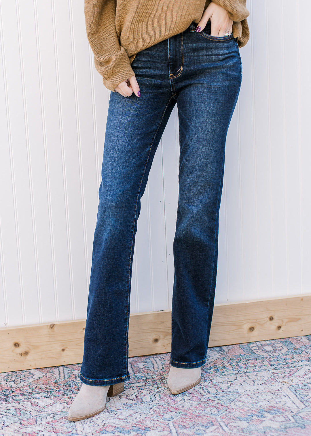 Model wearing mid rise, dark wash jeans with a boot cut and stretchy fit.