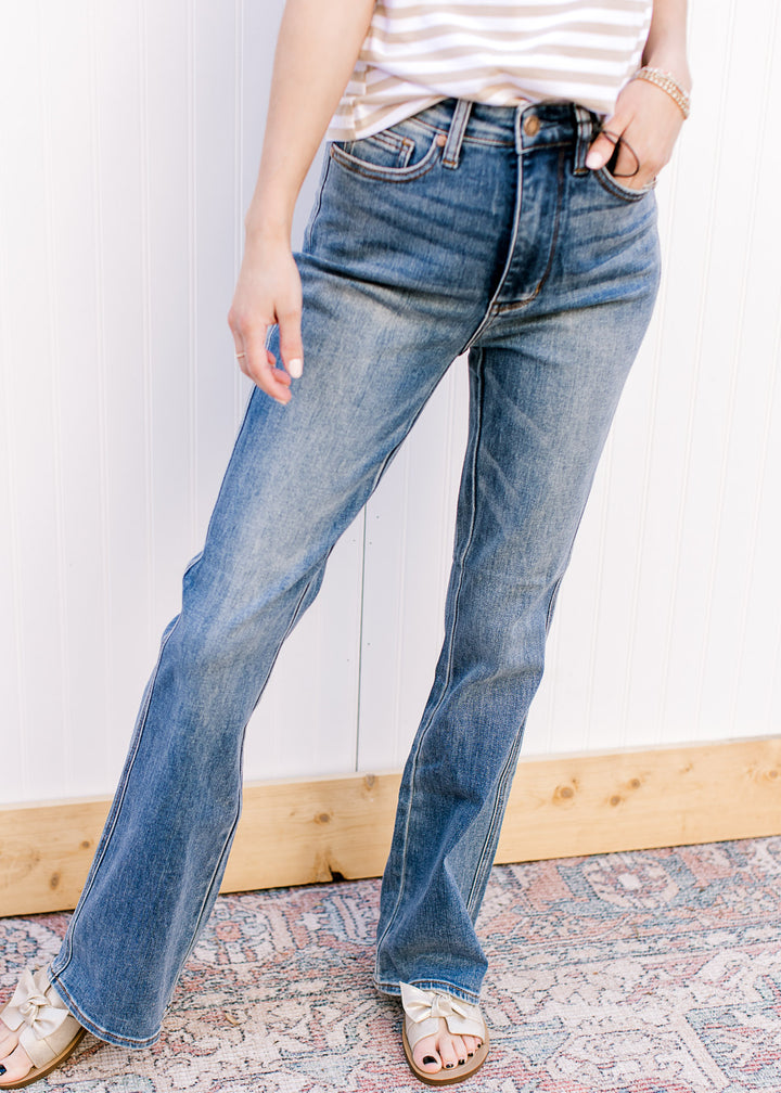 Model wearing boot cut medium wash jeans with tummy control and a high waist fit.