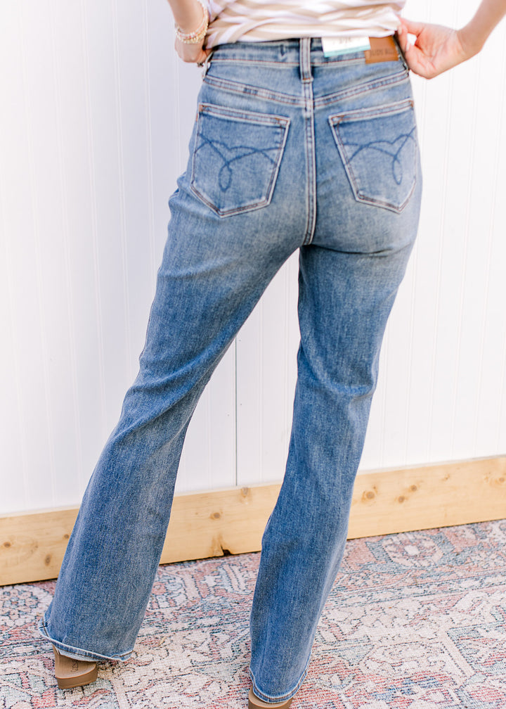 Back view of Model wearing boot cut medium wash jeans with a high waist fit.
