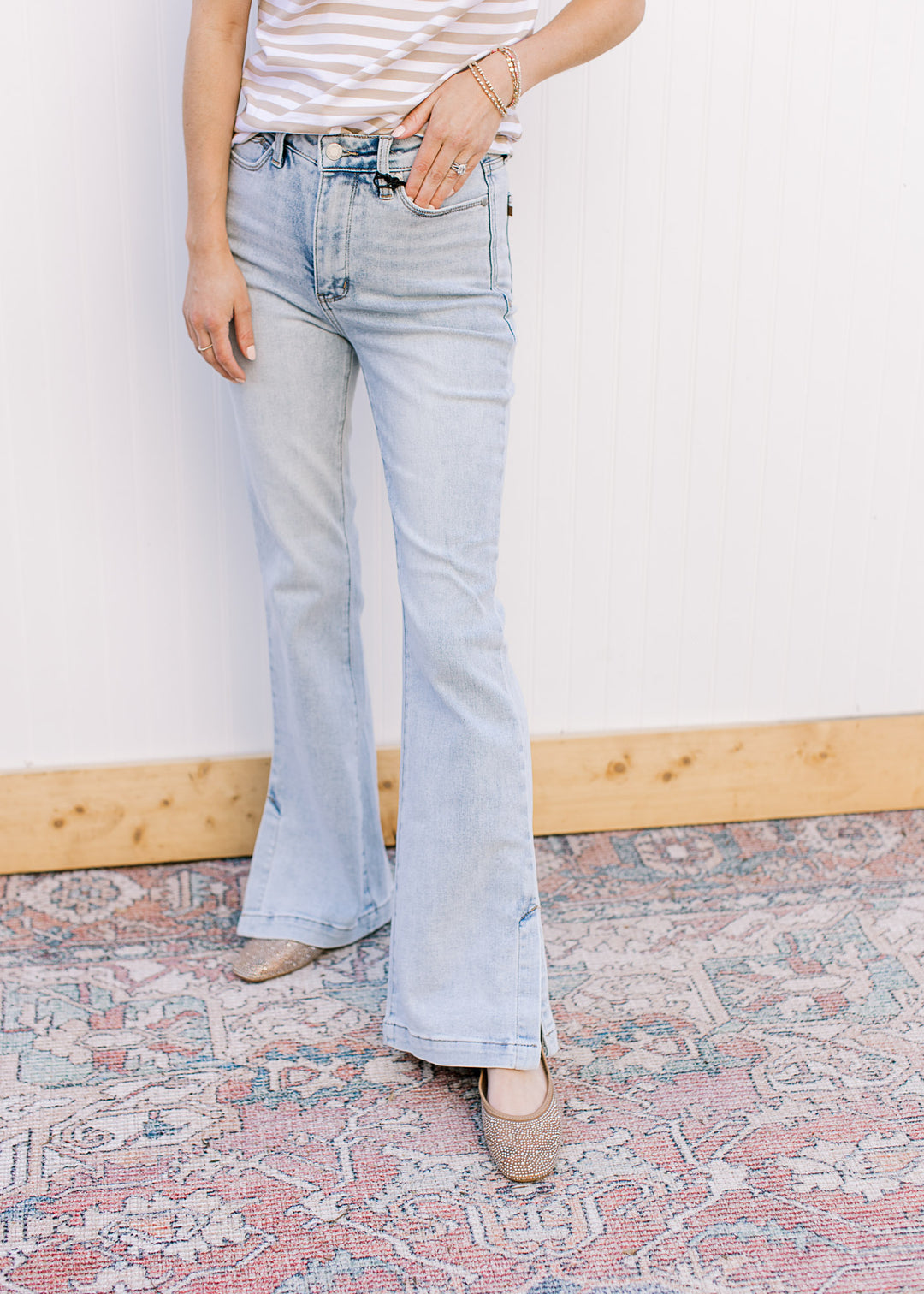 Model wearing lightwash bootcut jeans with side slits and a built in tummy control.
