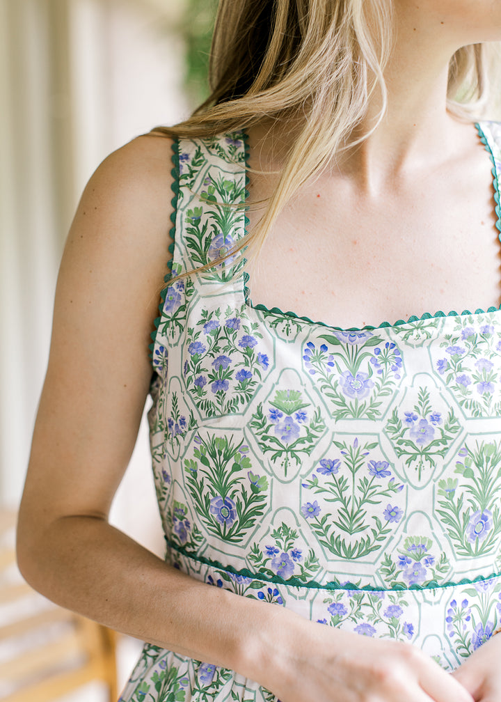 Close up of scallop detail and square neck on a white sleeveless id with green and blue floral.