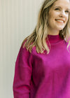 Close up of mock neck and drop sleeve on a magenta sweater with split sides and long sleeves. 
