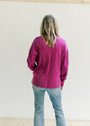 Back view of a model waring a magenta colored sweater with dropped shoulder and long sleeves. 