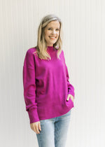Model wearing a magenta sweater with dropped shoulders, mock neckline and long sleeves. 