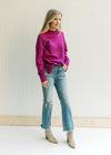 Model wearing booties, jeans and a magenta sweater with long sleeves, mock neck and split sides. 