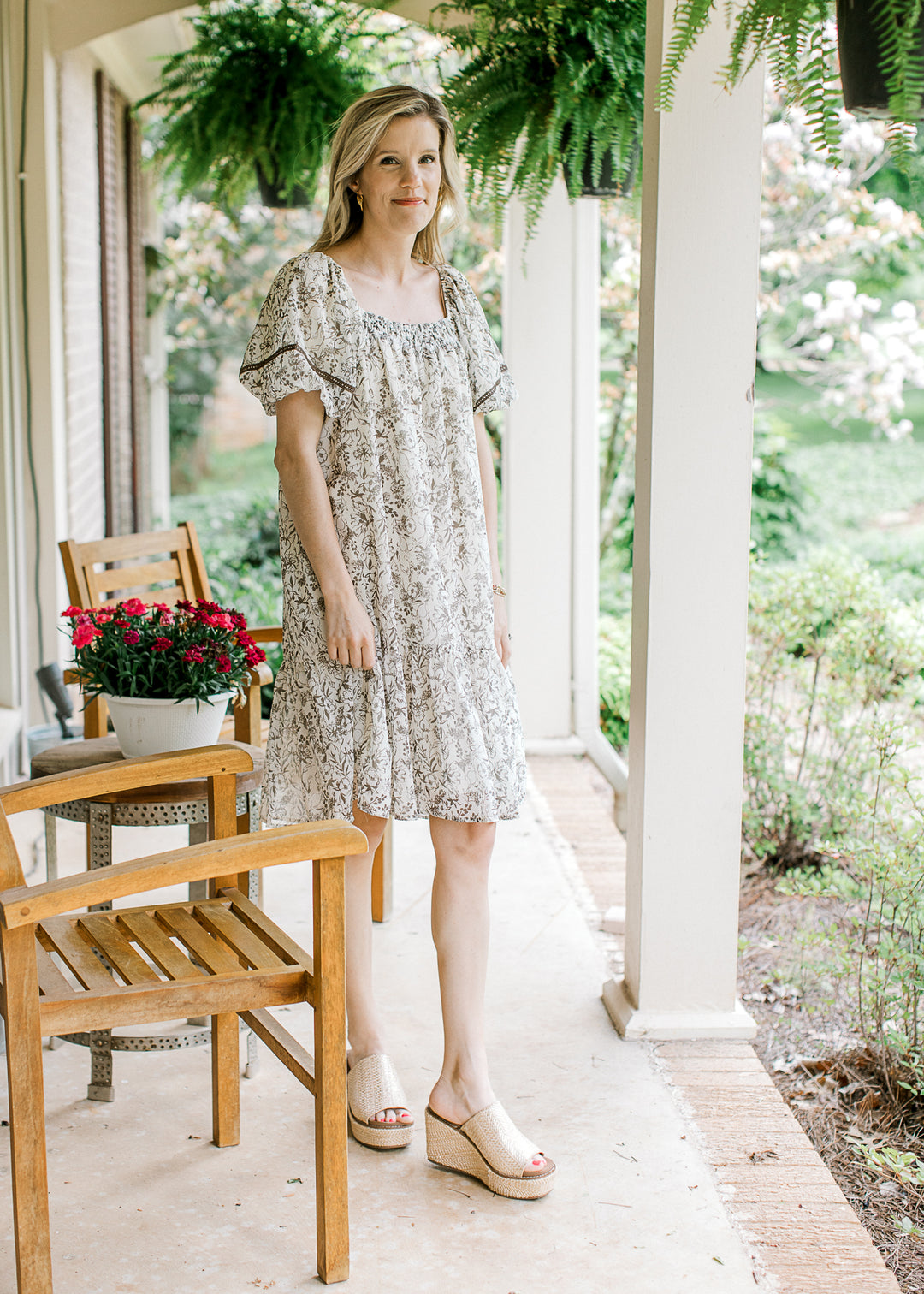 Model wearing wedges and a cream short sleeve dress with mocha floral and square neck.