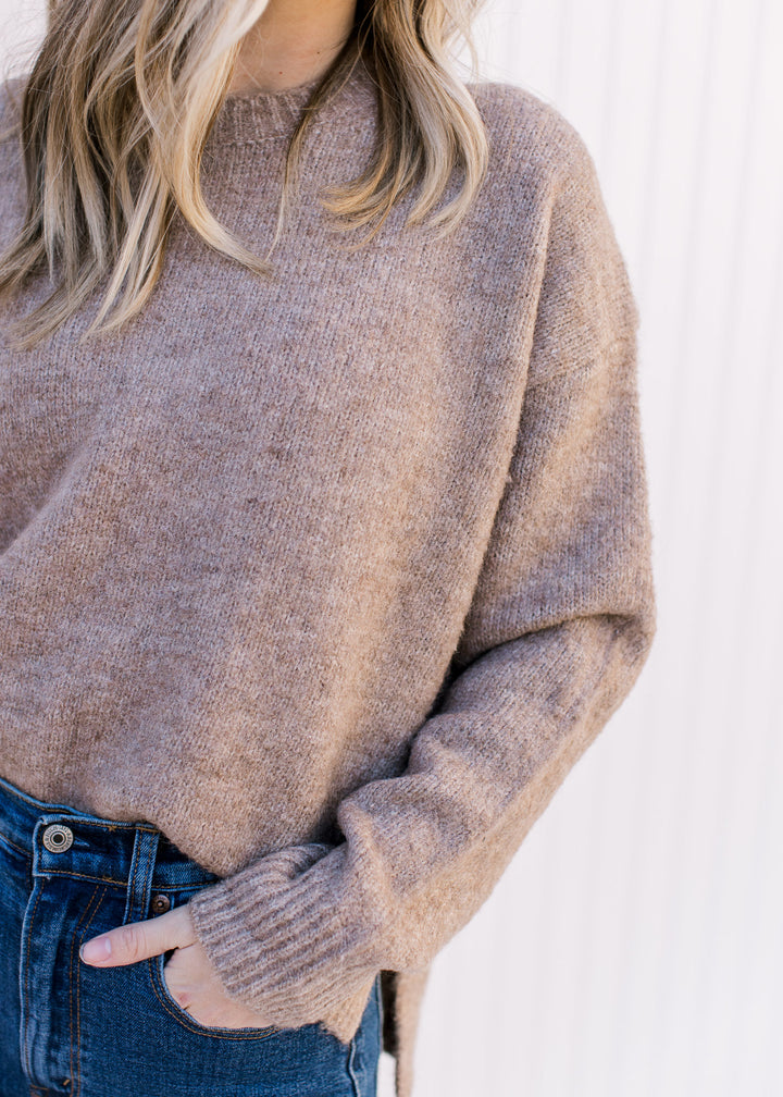 Close up of ribbed detailing and round neck on a model wearing a taupe, long sleeve sweater.