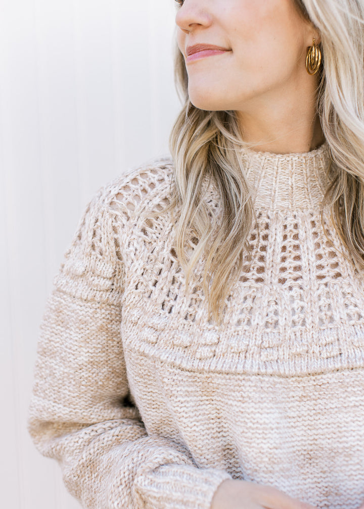Close up of open knit yolk and mock neck on an oatmeal colored sweater with long sleeves.