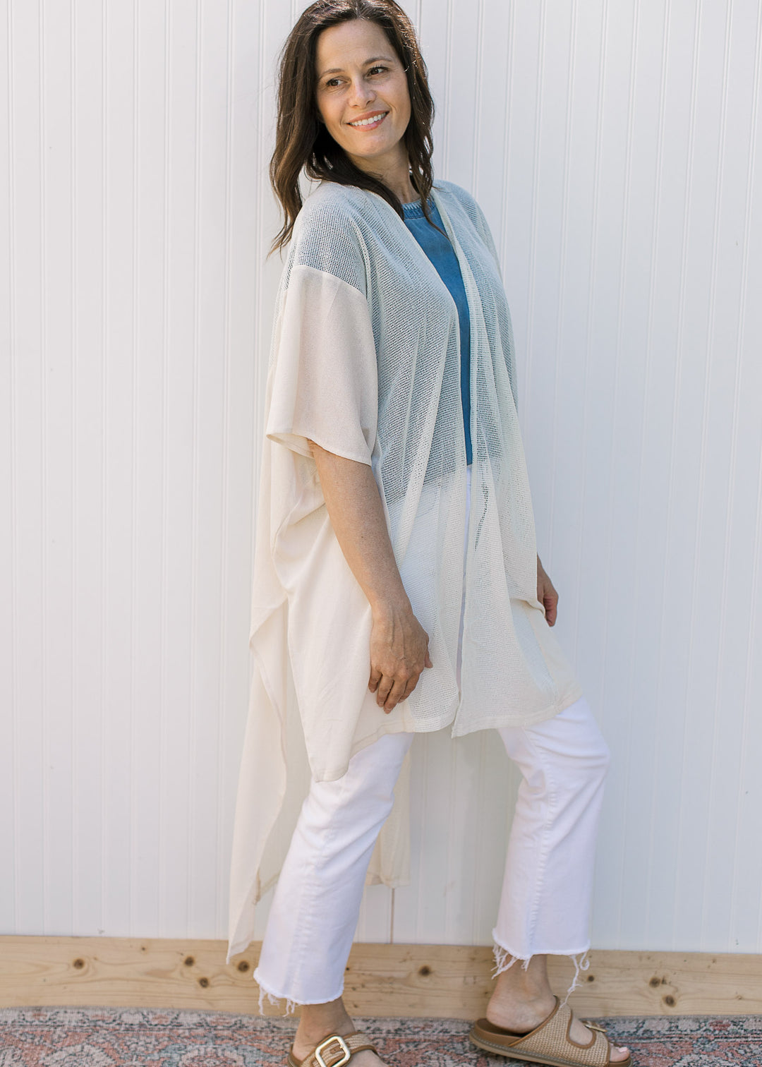 Side view of model wearing a cream, maxi duster with a sheer woven fabric with light knit inset.