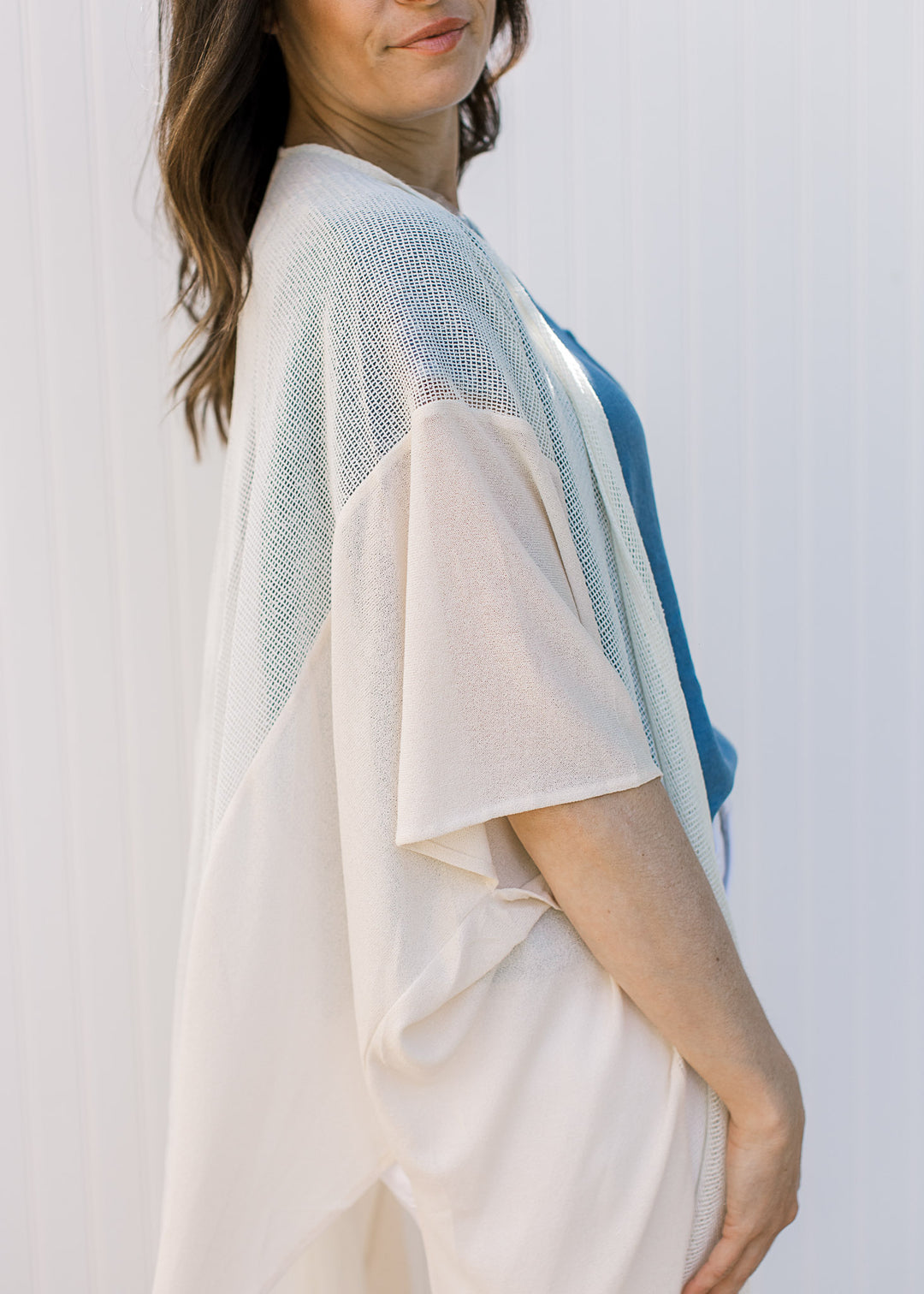 Close up view of short sleeve on a cream, maxi duster with a sheer fabric with light knit inset.