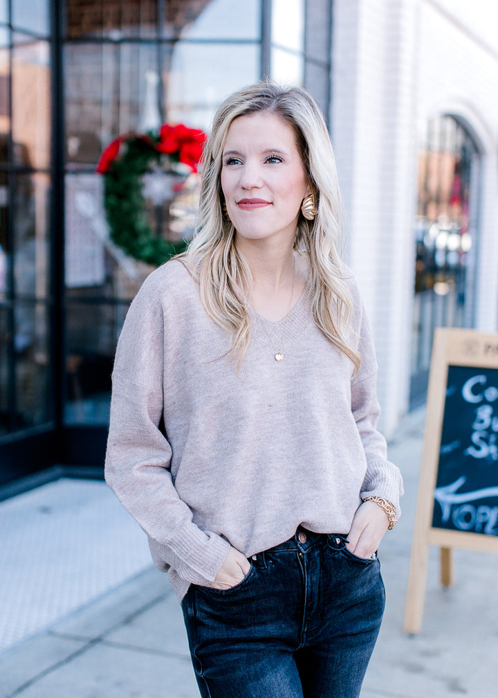 Model wearing a wheat v-neck sweater with long sleeves and ribbed neck, hem and cuff.