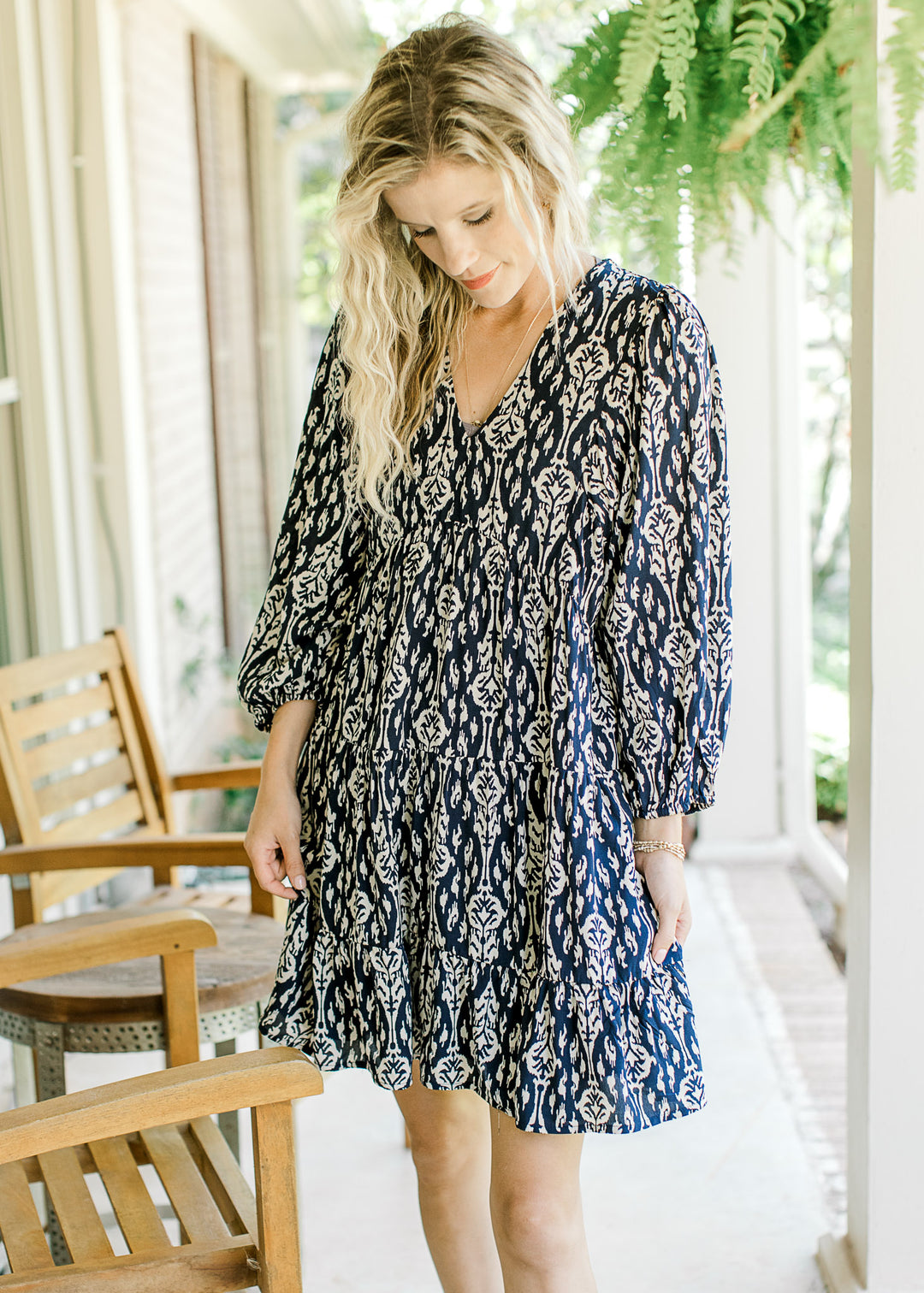 Model wearing a navy dress with taupe floral pattern, 3/4 sleeve and a v-neck.