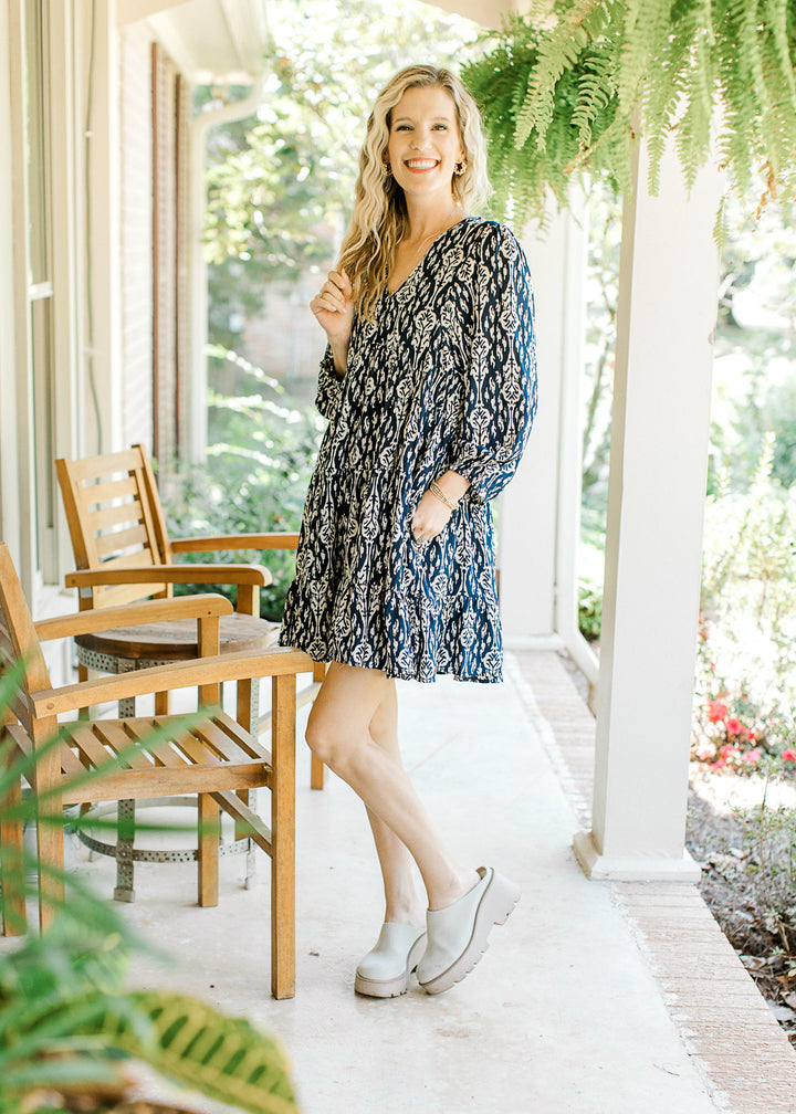 Model wearing wedges with a navy dress with taupe floral pattern, 3/4 sleeve and a v-neck.