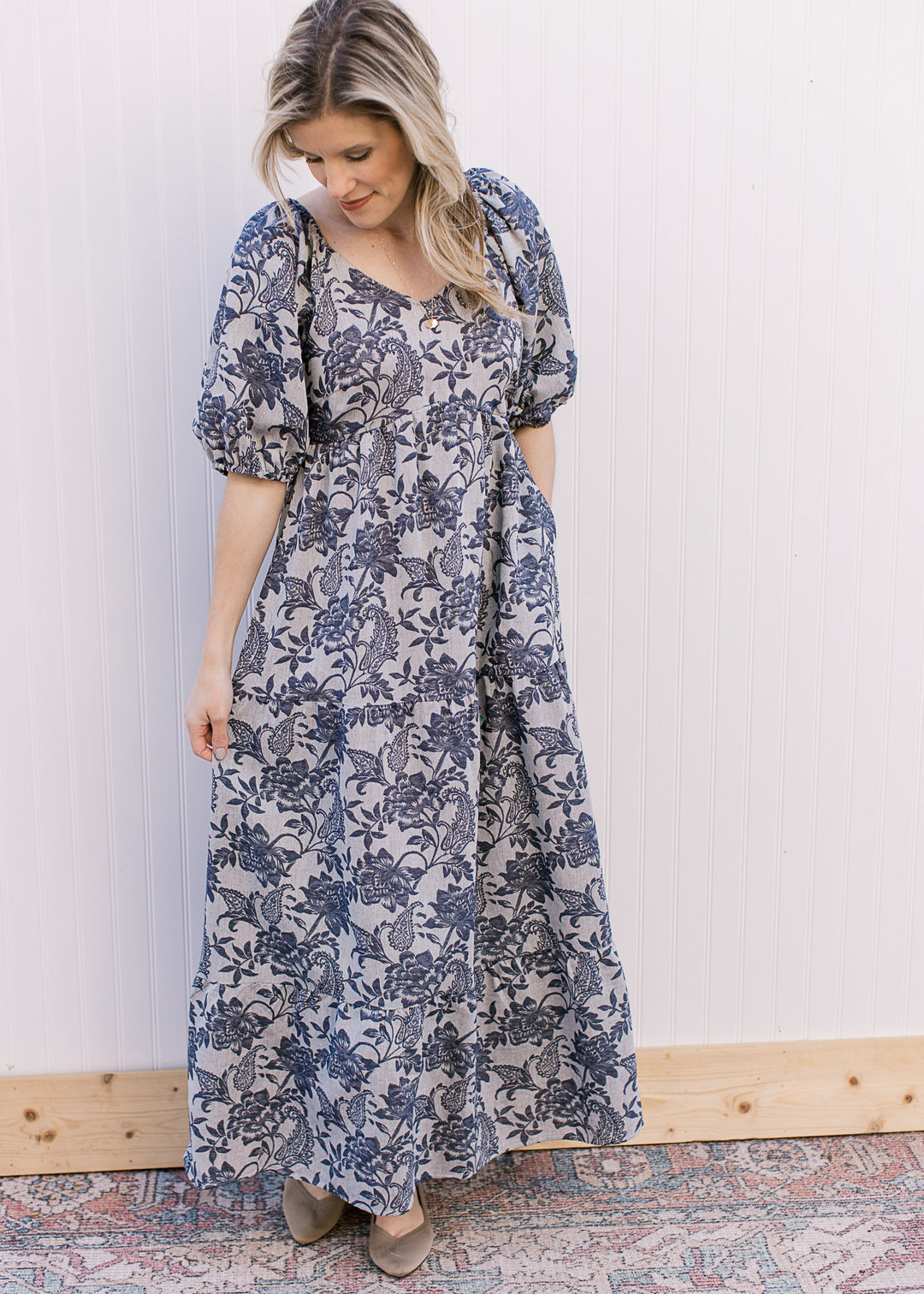 Model wearing flats and a gray maxi with navy floral, short puff sleeves and a v-neck.