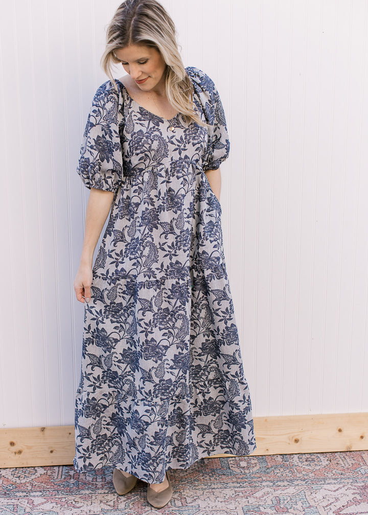 Model wearing flats and a gray maxi with navy floral, short puff sleeves and a v-neck.