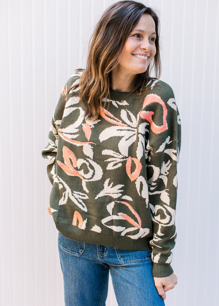 Model wearing a super soft olive sweater with cream flowers and coral accents.