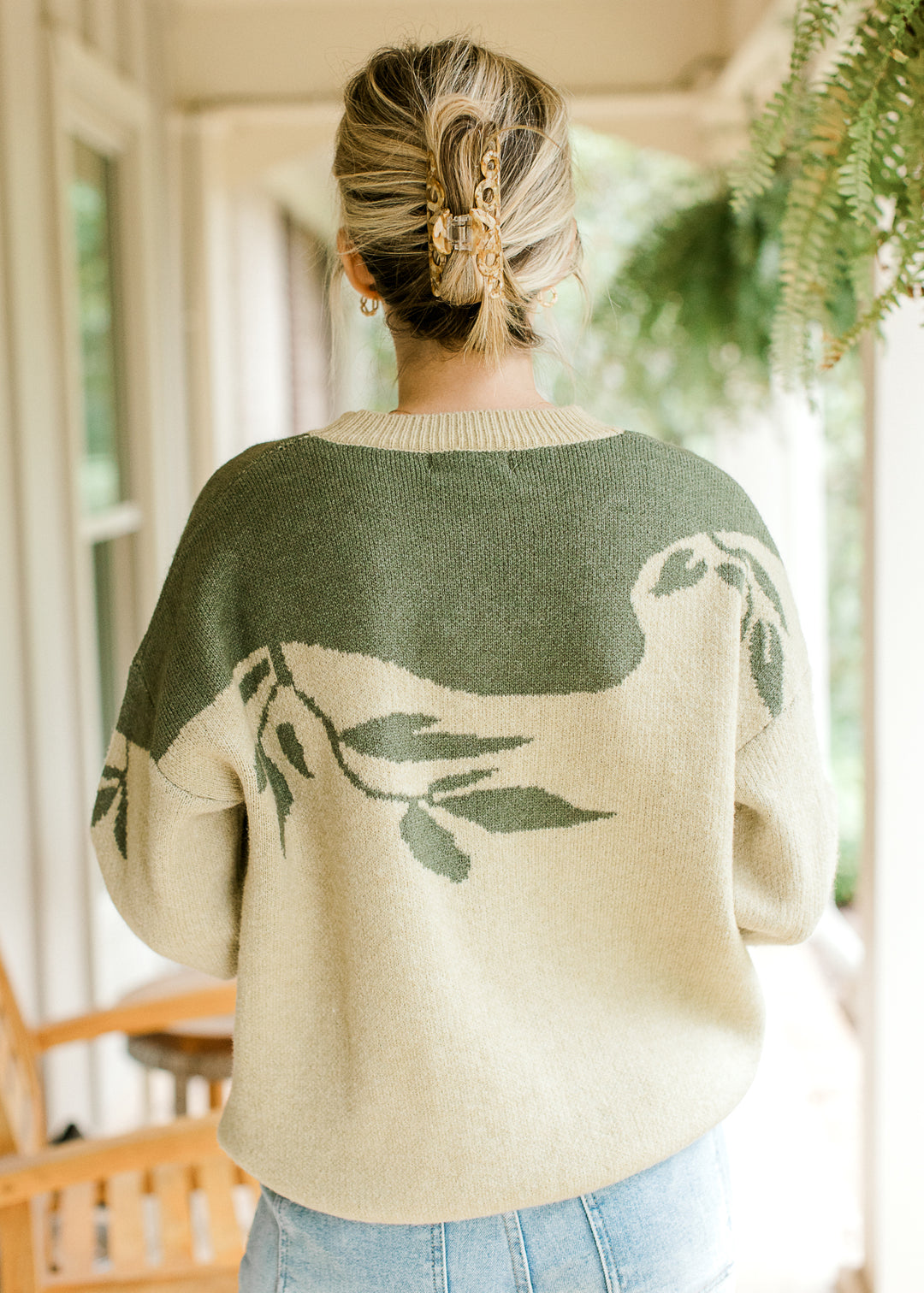 Back view of Model wearing a sage sweater with olive tree detail, long sleeves and round neck.