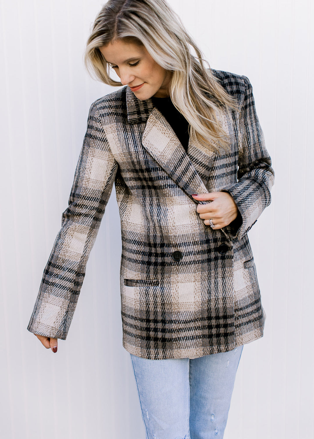 Model wearing a long sleeve cream and black plaid jacket with button closure and a collar.