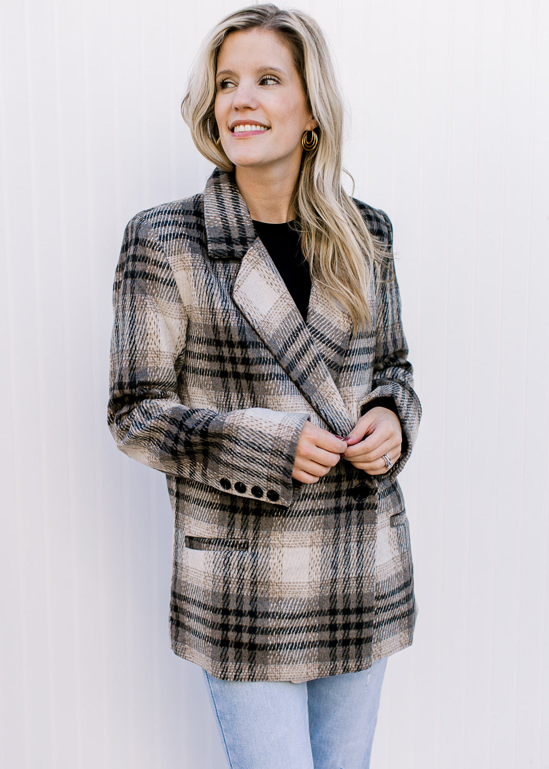 Model wearing a black top with a cream and black plaid jacket with button closure and collar.