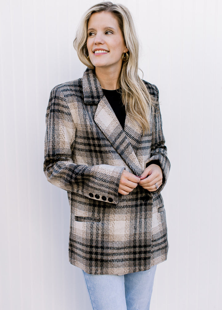 Model wearing a black top with a cream and black plaid jacket with button closure and collar.