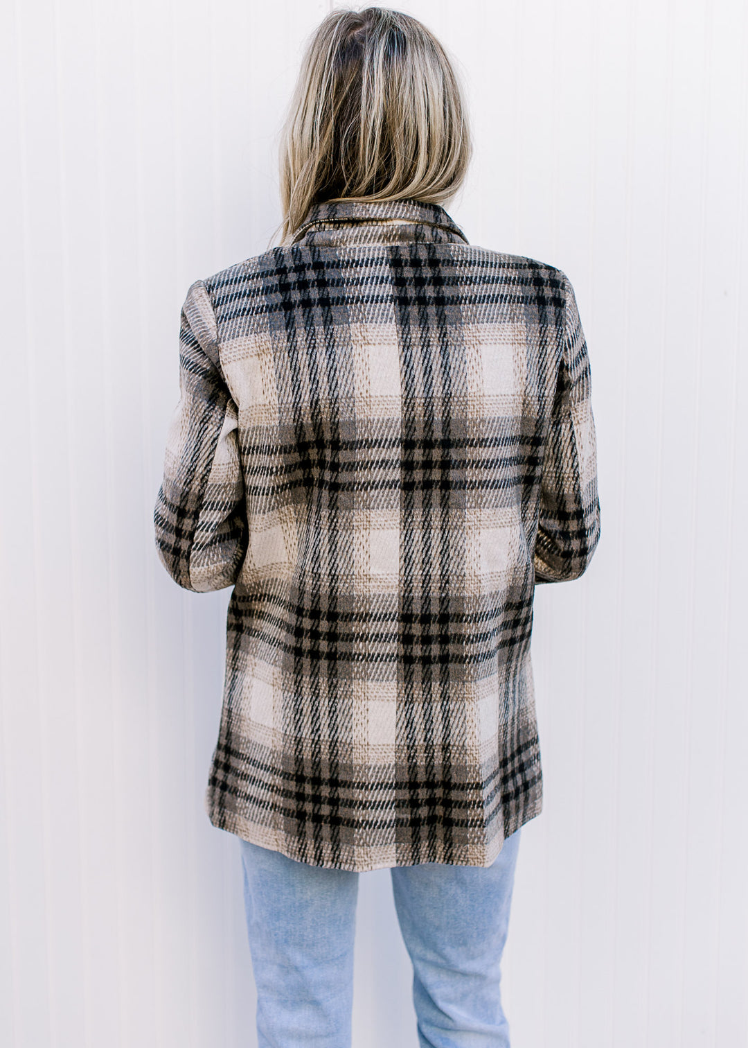 Back view of Model wearing a cream and black plaid polyester  jacket with a collar.