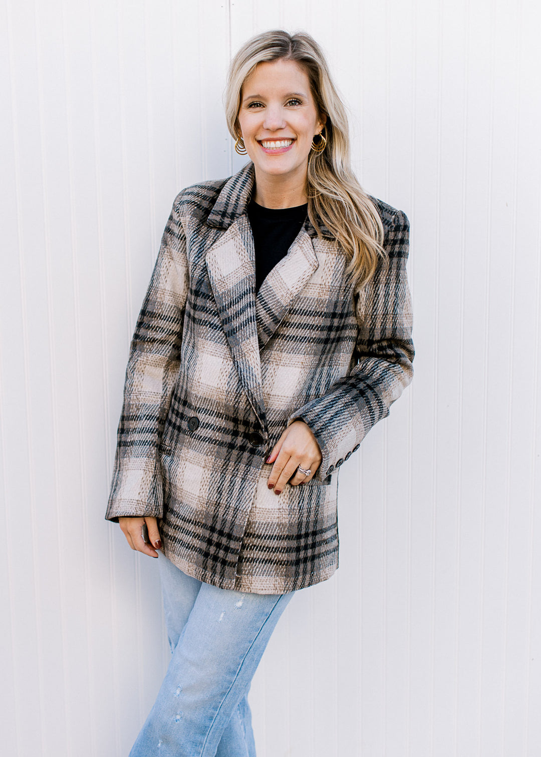 Model wearing jeans with a cream and black plaid jacket with single button closure.