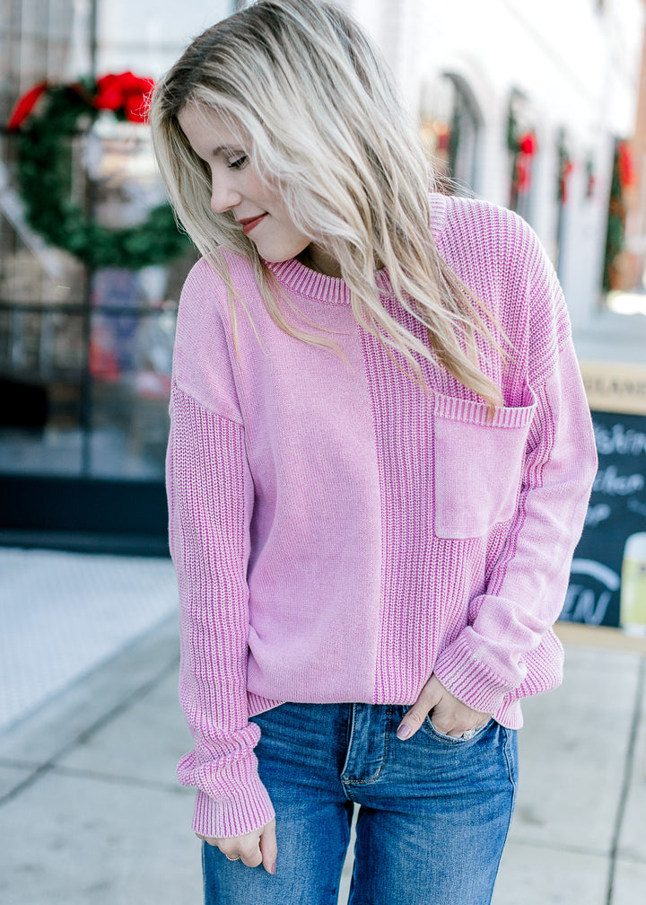 Model wearing jeans and a pink sweater with two styles of textured knit and a front patch pocket.
