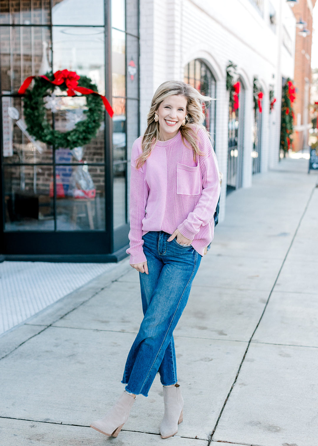 Model wearing jeans, booties and a pink long sleeve sweater with two styles of textured knit.
