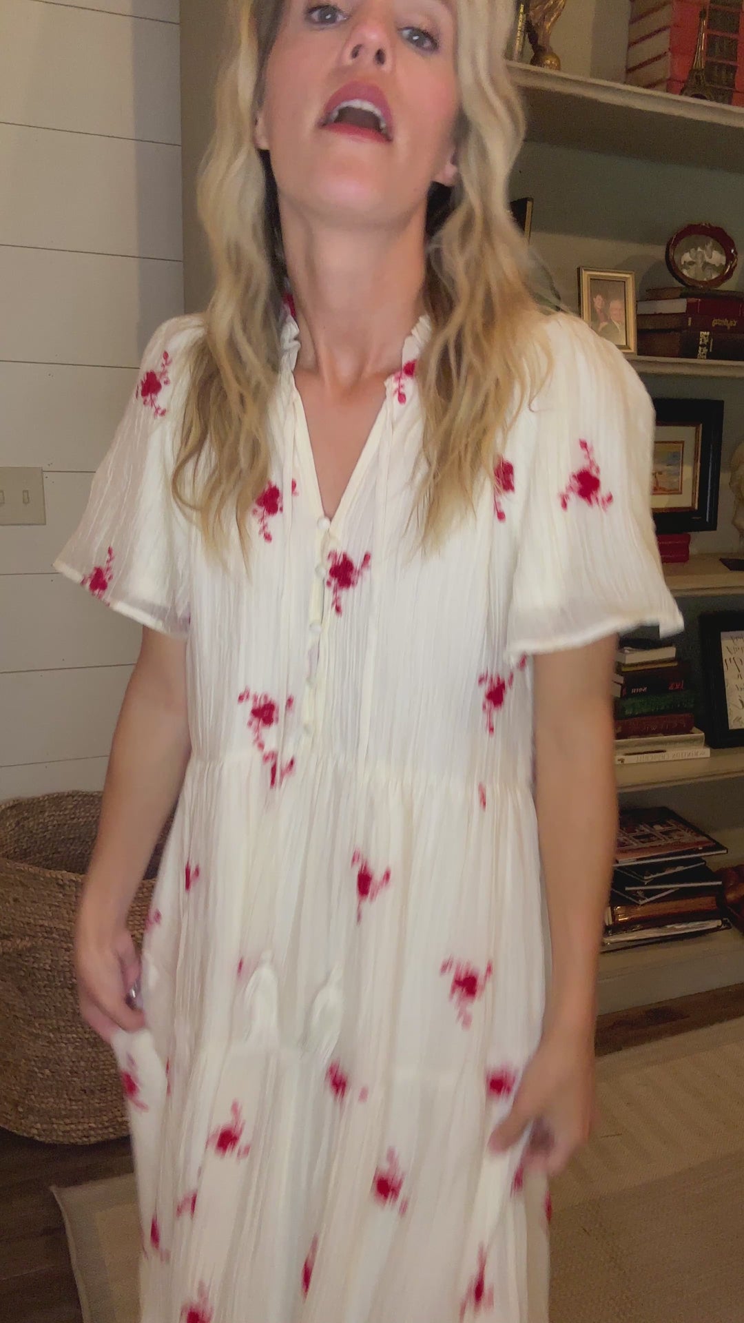 Video of Model wearing a white maxi with red flowers, crinkle material, short sleeves and a v-neck.