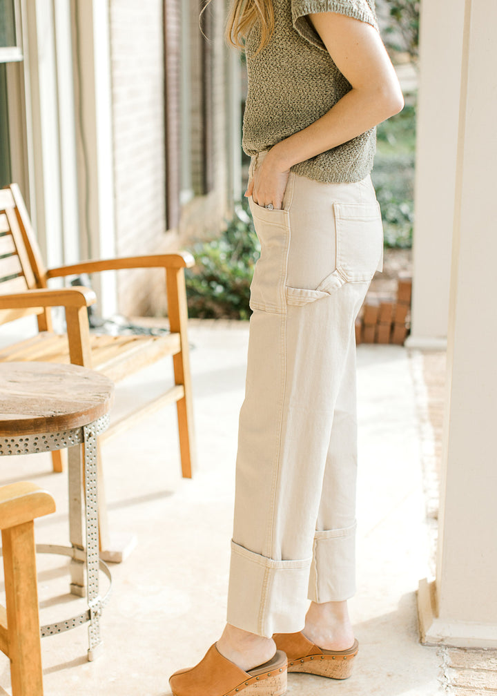 Model wearing light khaki cargo jeans with  high waist and wide legs with large cuff at bottom.