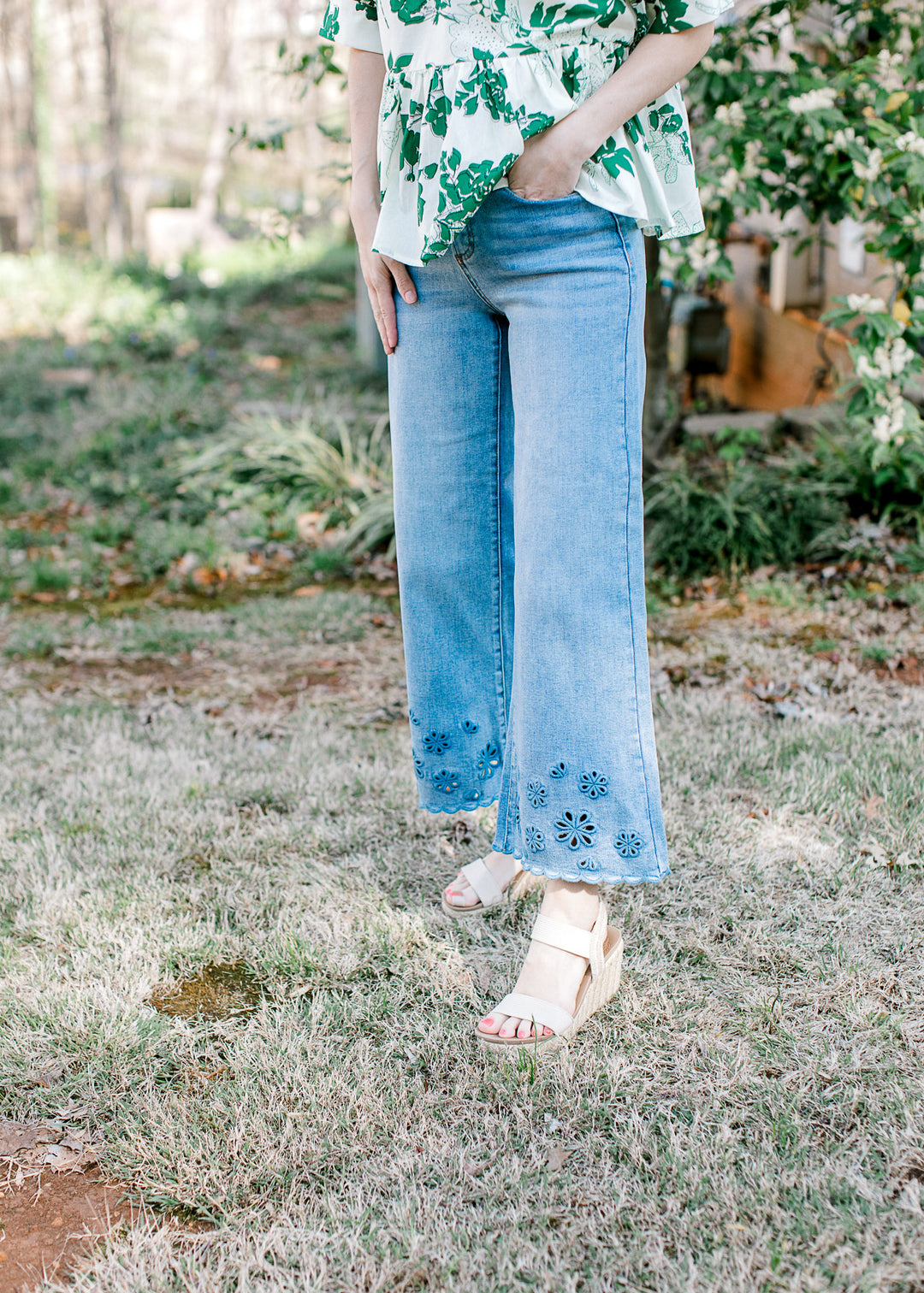 Model wearing heels with medium wash jeans with a cropped wide leg fit and floral at hem.