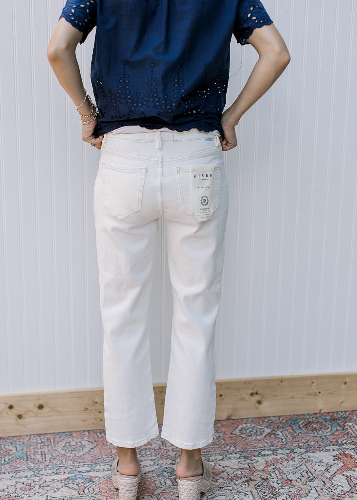 Back view of Model wearing cream midrise, straight pants with a cropped fit.