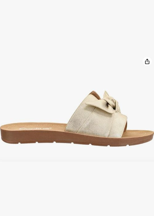 Side view of a gold slip on sandal with a single wide strap with bow detail and a cushioned footbed.