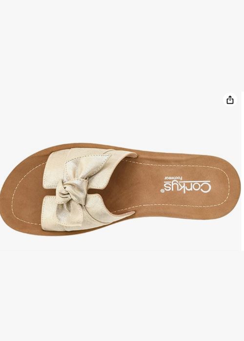 Top down view of a gold slip on sandal with a single wide strap with bow detail.