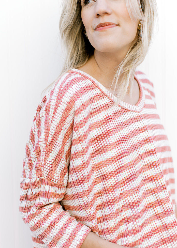 Side view of Model wearing a knit cream and rose top with v-neck, side slit and 3/4 sleeves.