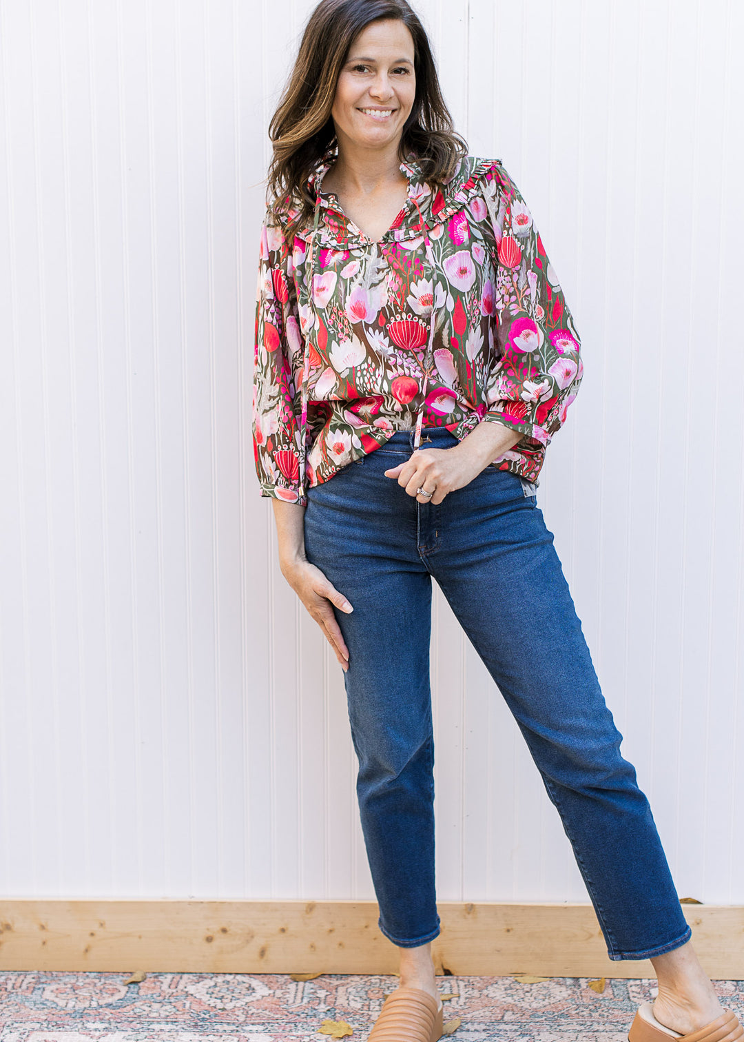 Model wearing a brown top with pink flowers, 3/4 sleeves and v-neck with a tie.