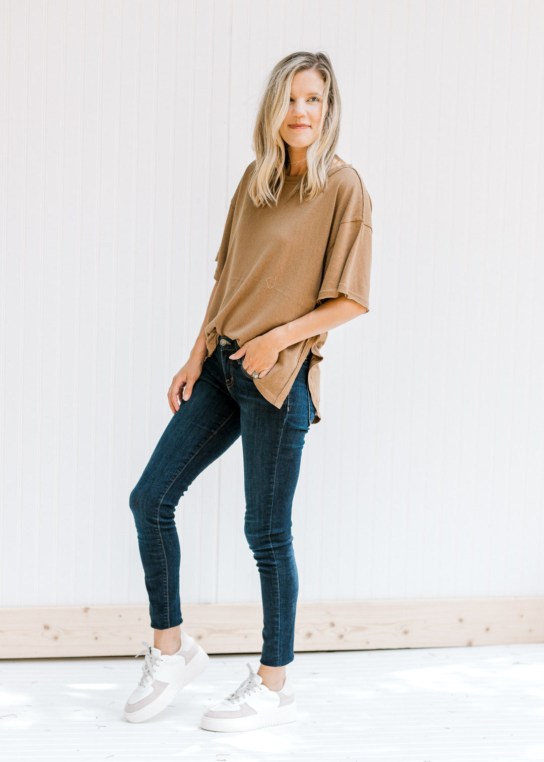 Model wearing jeans and a top with a white and taupe shoe with a platform sole and laces.
