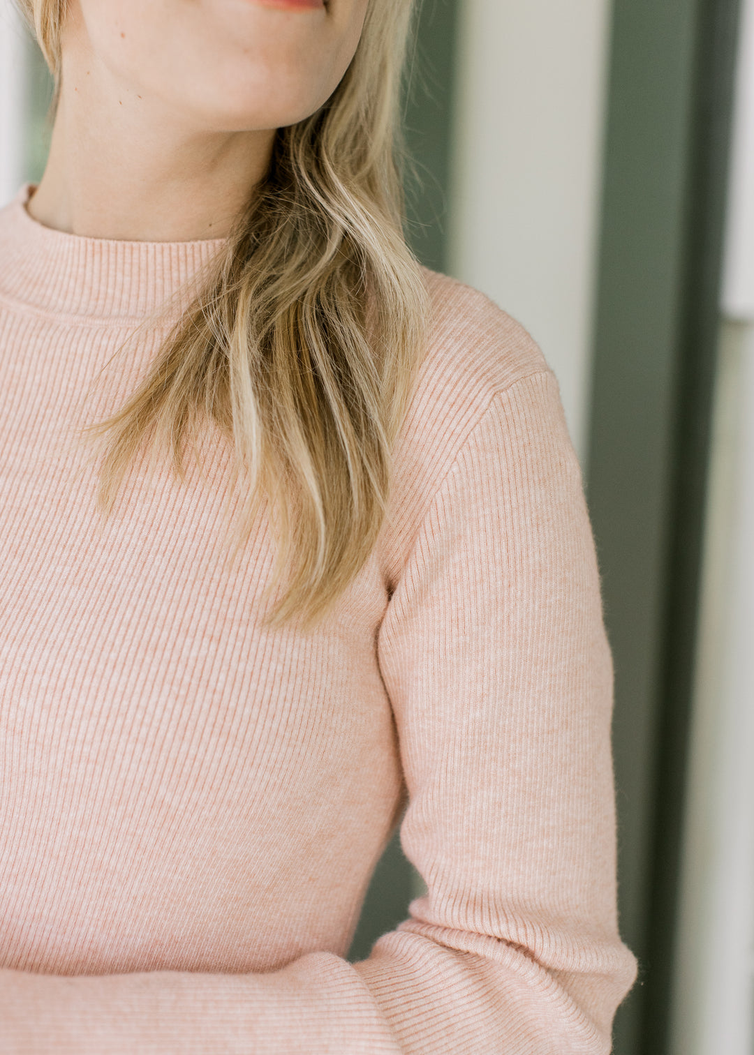 Close up of mocked neck and ribbed material on a blush lightweight sweater with long sleeves.