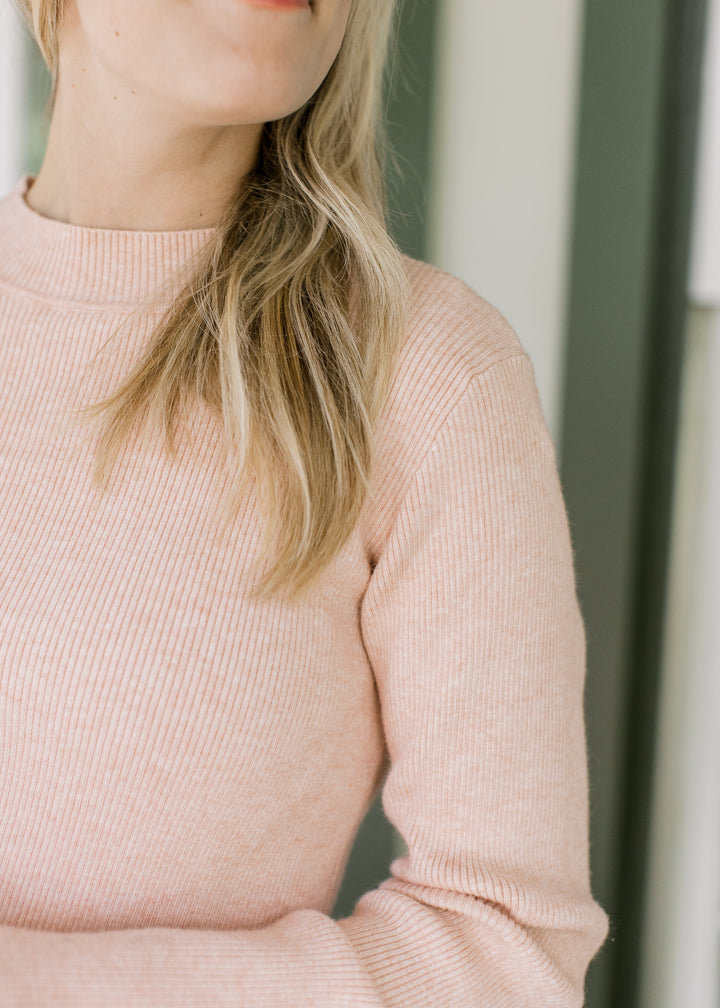 Close up of mocked neck and ribbed material on a blush lightweight sweater with long sleeves.