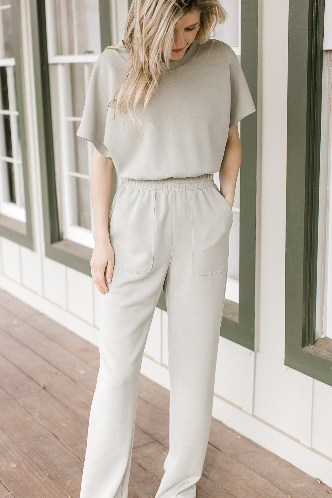 Model wearing a sage jumpsuit with an elastic waist, short sleeves and a boatneck.