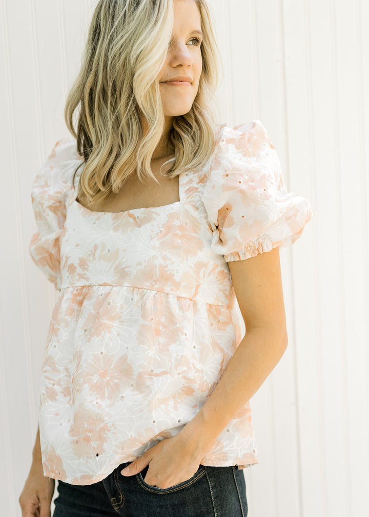 Model wearing a white and coral embroidered floral top with a square neck and bubble short sleeves.