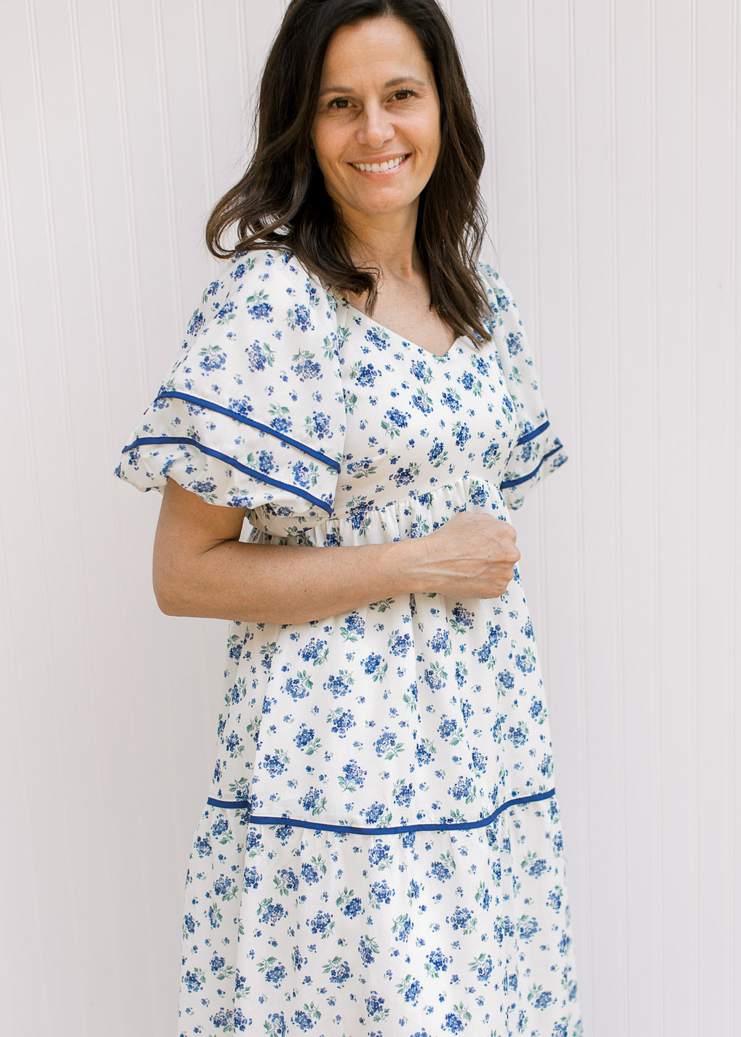 Model wearing a cream maxi with blue floral, bubble short sleeves, v-neck and pockets.