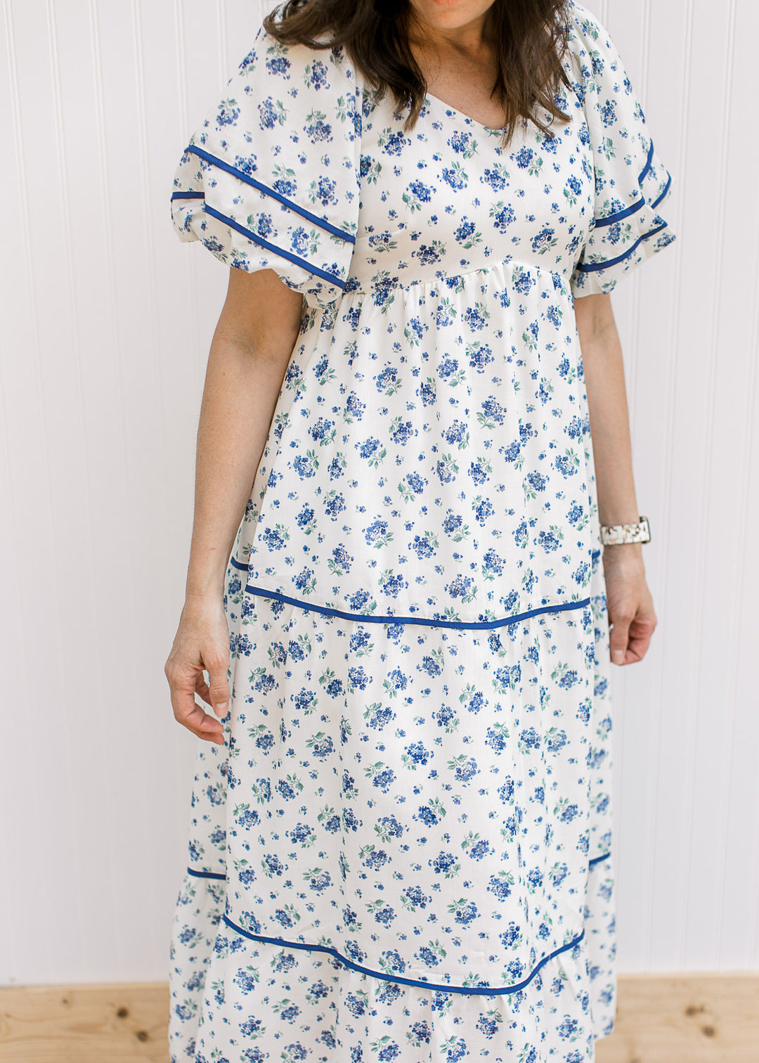 Close up of navy piping detail on a cream maxi with blue floral, bubble short sleeves and a v-neck.