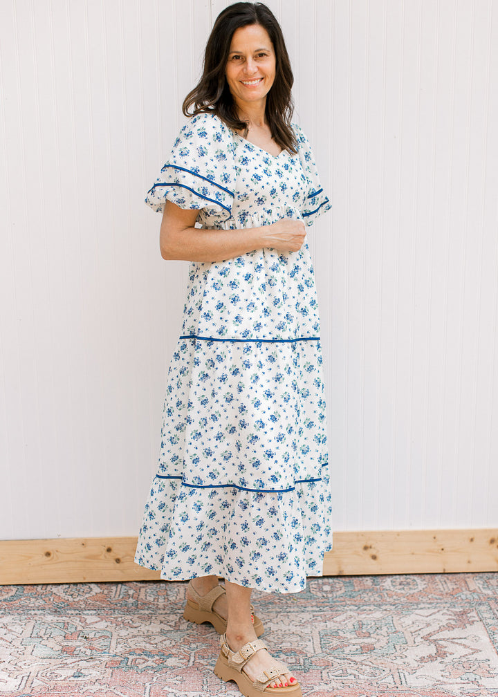 Side view of model wearing a cream maxi with blue floral, bubble short sleeves, v-neck and pockets.