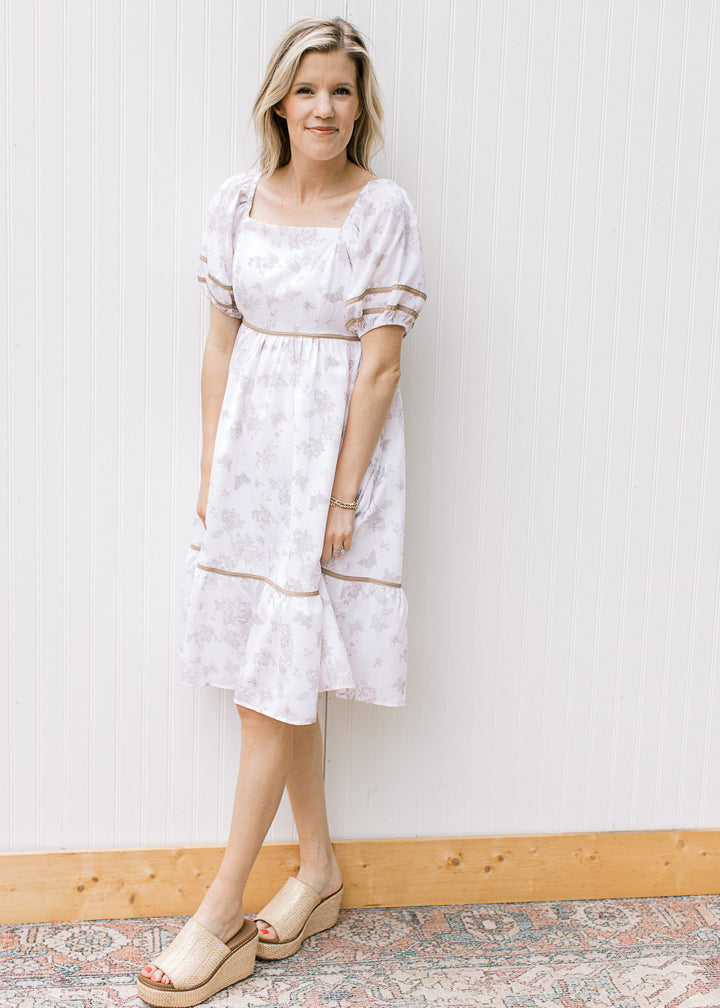 Model wearing wedges and a cream dress with wheat color piping, square neck and bubble short sleeve