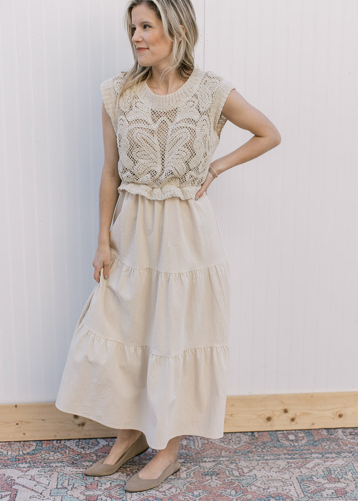 Model wearing a taupe maxi with cap sleeves, openwork crochet top and a tiered skirt.