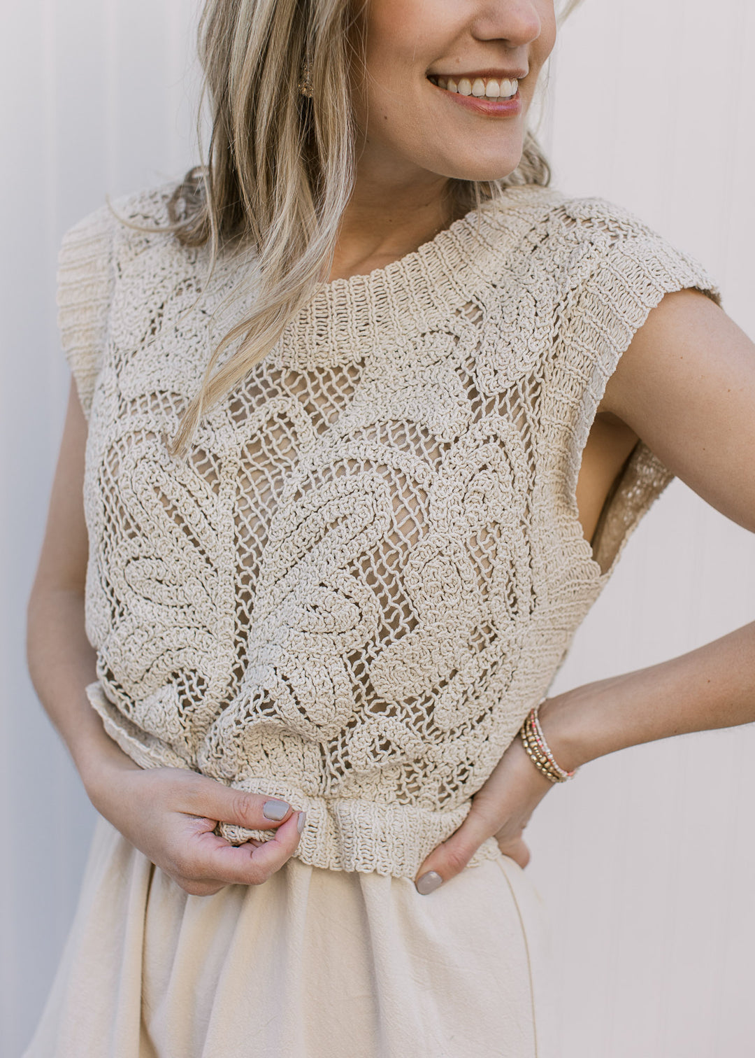 Close up of openwork knit top and cap sleeve on a taupe maxi with a tiered skirt.